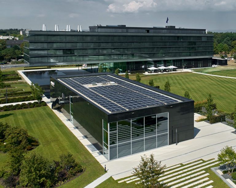 Moderner Gebäudekomplex der Area3 mit Solardach und großer Grünanlage von oben