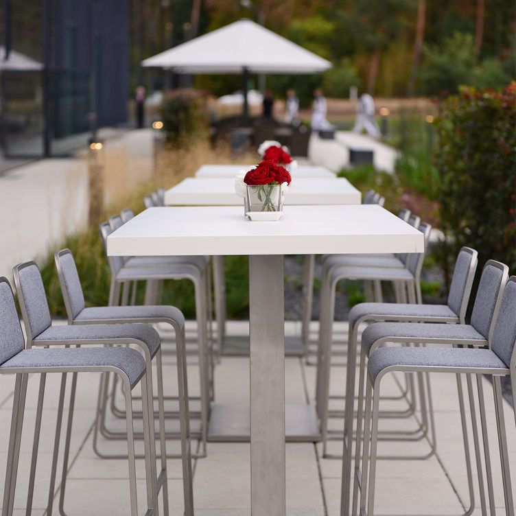 Barhocker um weiße Tische mit roten Rosen drauf