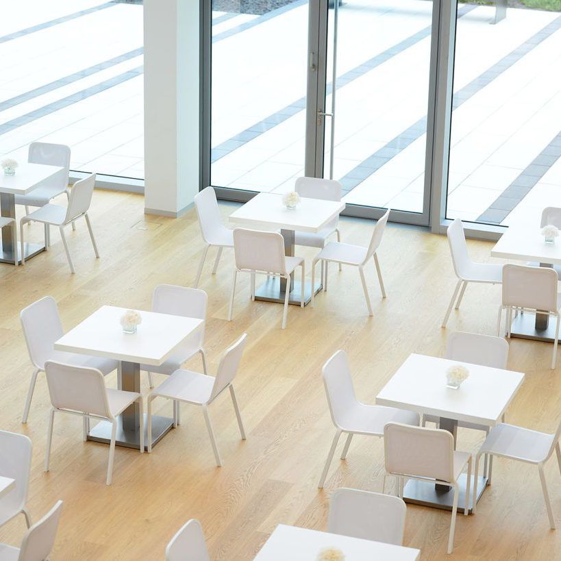 Heller Raum mit weißen Tischen und Stühlen.