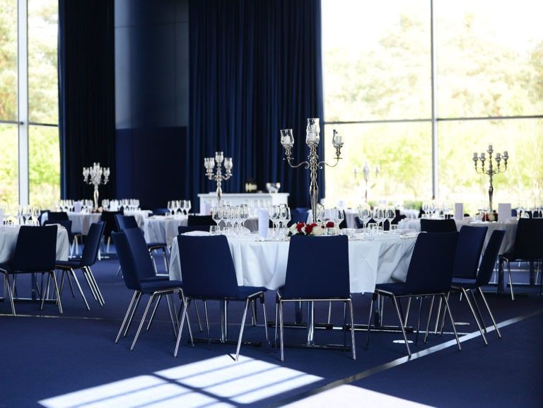 Große, runde Tische mit weißen Tischdecken und silbernen Kerzenhaltern.