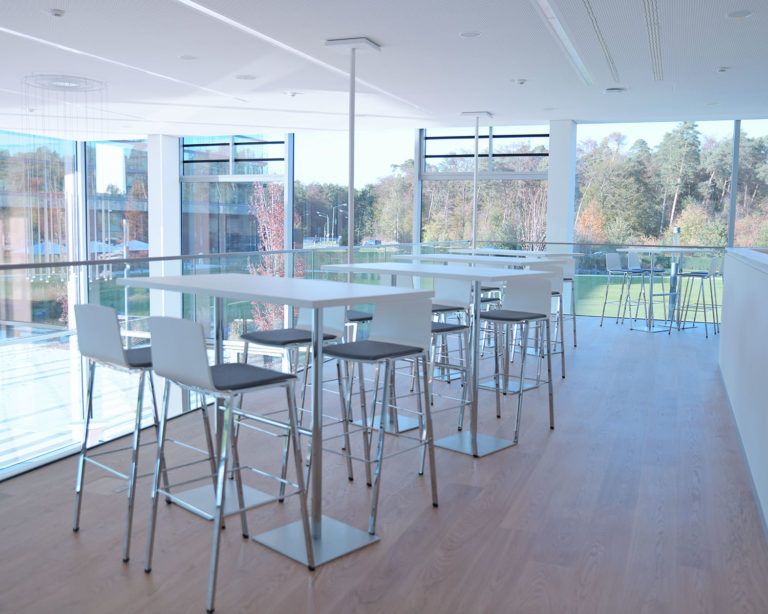 Galerie, mit Barhockern und hellen Tischen mit Blick nach draußen